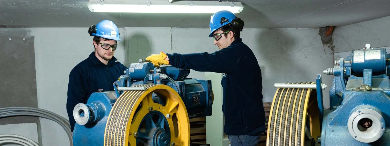 Técnicos de De La Roca Ascensores realizando mantenimiento en una sala de máquinas